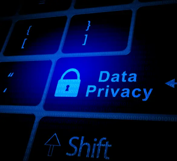 A close-up of a keyboard with a glowing blue key featuring a padlock icon and the words Data Privacy next to it. Other keys, including Shift and bracket symbols, are also visible with blue backlighting and binary code patterns across the surface.